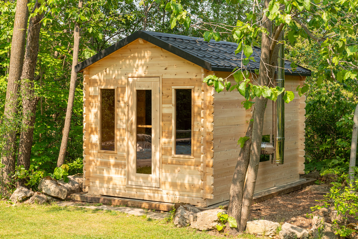 Angled view of the LeisureCraft Georgian cabin sauna in Eastern White Cedar in a wooded backyard