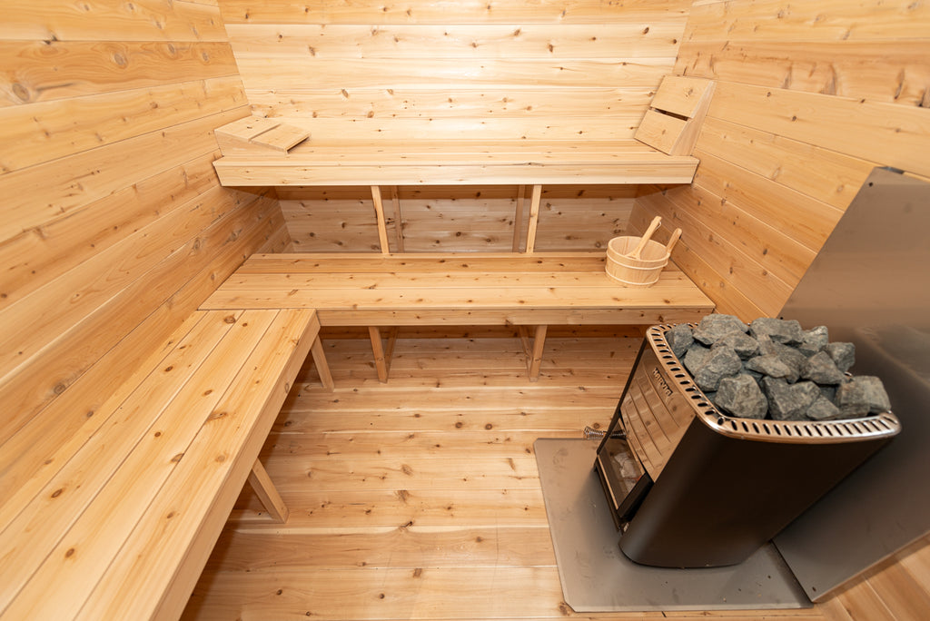Georgian cabin sauna room with two-tier cedar benches and wood-burning heater with sauna stones