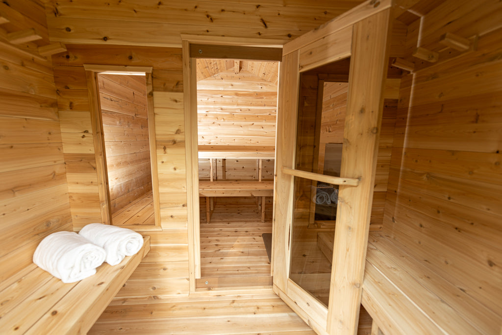 Georgian cabin sauna changeroom with bench and towels, opening into the sauna room